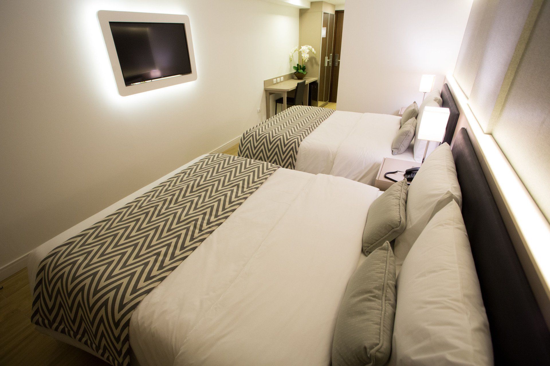Um quarto de hotel com duas camas e uma TV de tela plana na parede.