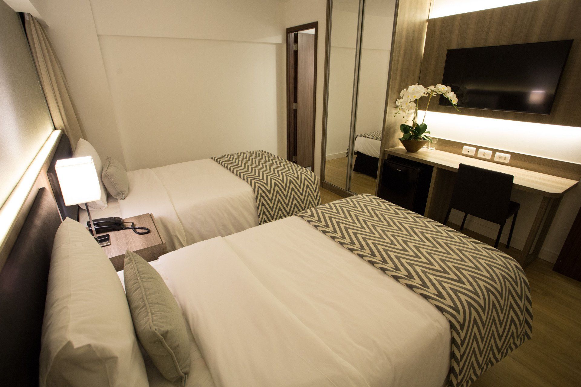 Um quarto de hotel com duas camas e uma TV de tela plana.