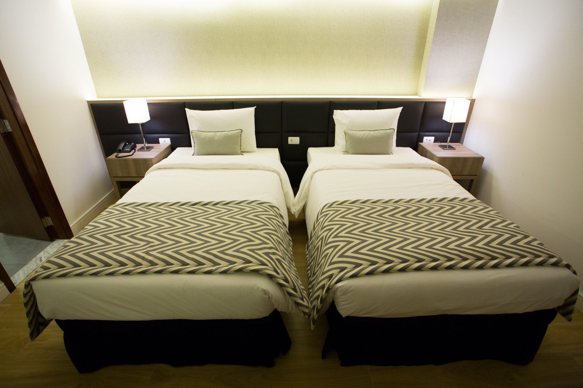 Um quarto de hotel com duas camas e duas mesas de cabeceira