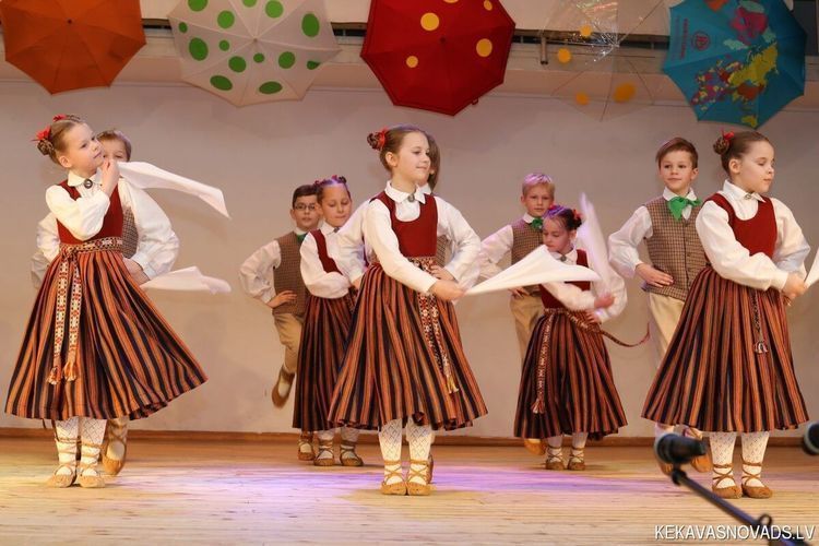 Skolēnu tautas deju ansamblis dejo uz skatuves ANVI AM izgatavotos latviešu tautastērpos