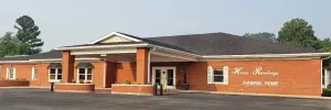 Low brick building with white trim and columns on a roadside under a cloudy sky
