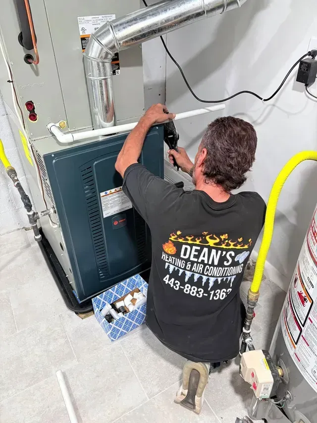 A person is working on an air conditioner with gauges attached to it.