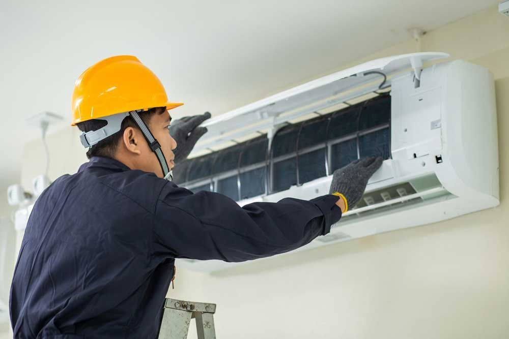 A man is fixing a water heater with a wrench.