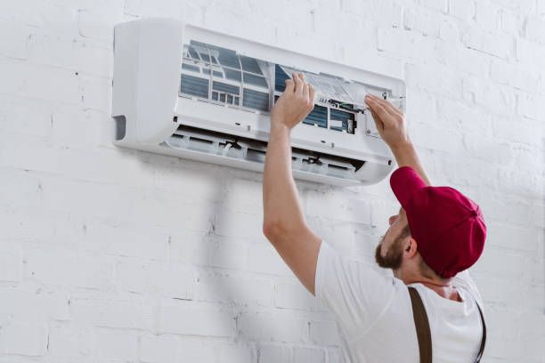 A man is fixing a water heater with a wrench.