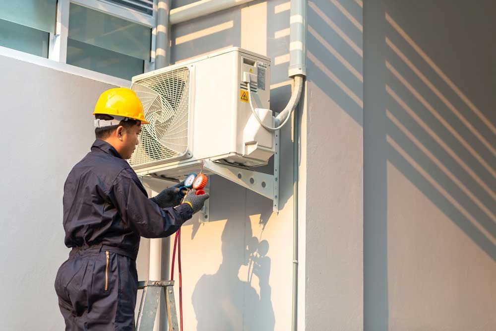 A man is working on an air conditioner on the side of a building.