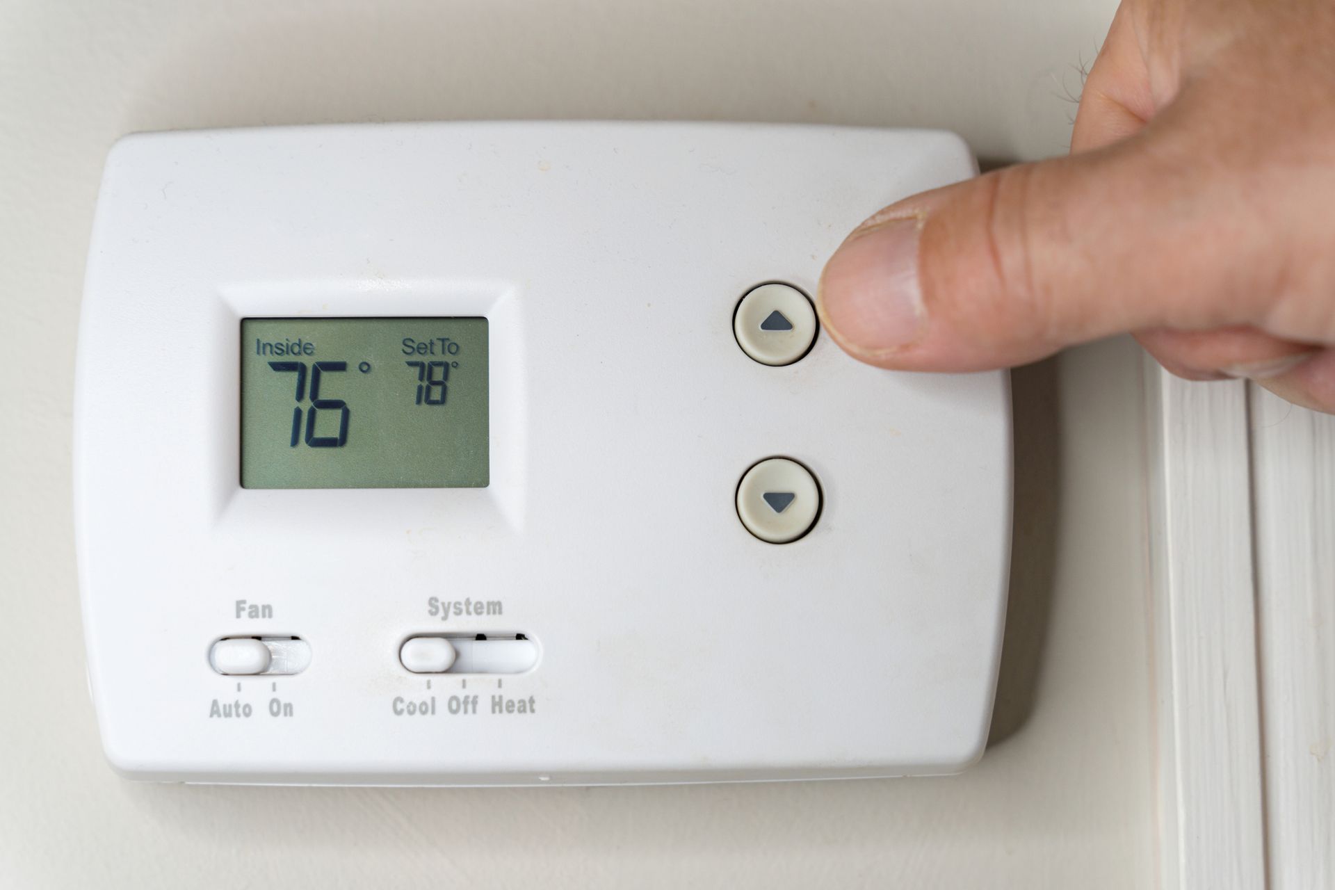 Homeowner adjusting the thermostat to control indoor air conditioning.