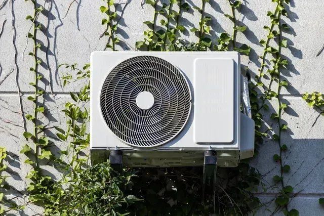 A white air conditioner is mounted on the side of a building.