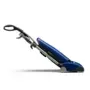 Blue upright vacuum cleaner on a white rug in a room with a desk, chair, and window.