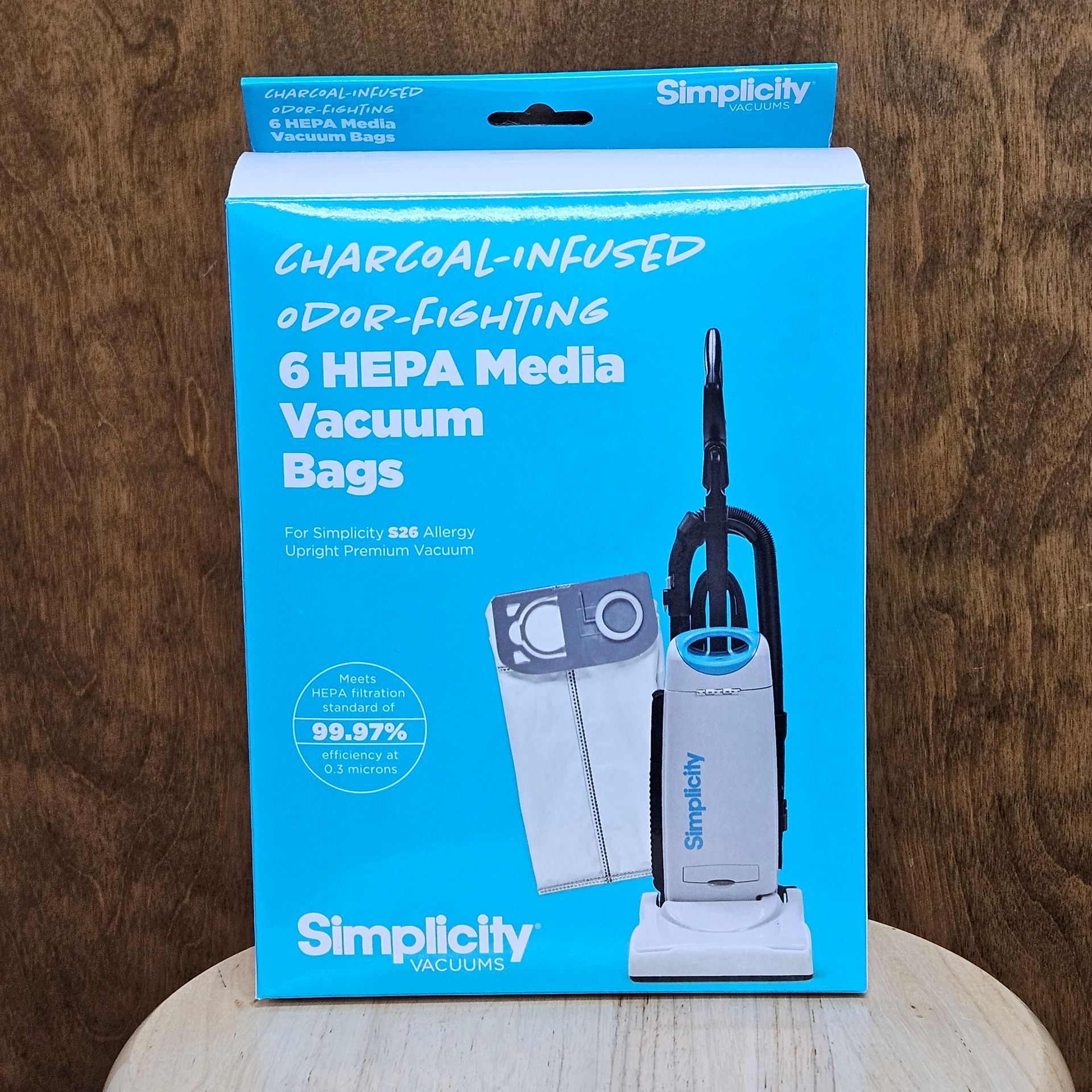 Box of six charcoal-infused HEPA media vacuum bags by Simplicity. Turquoise box with a vacuum cleaner and bag.