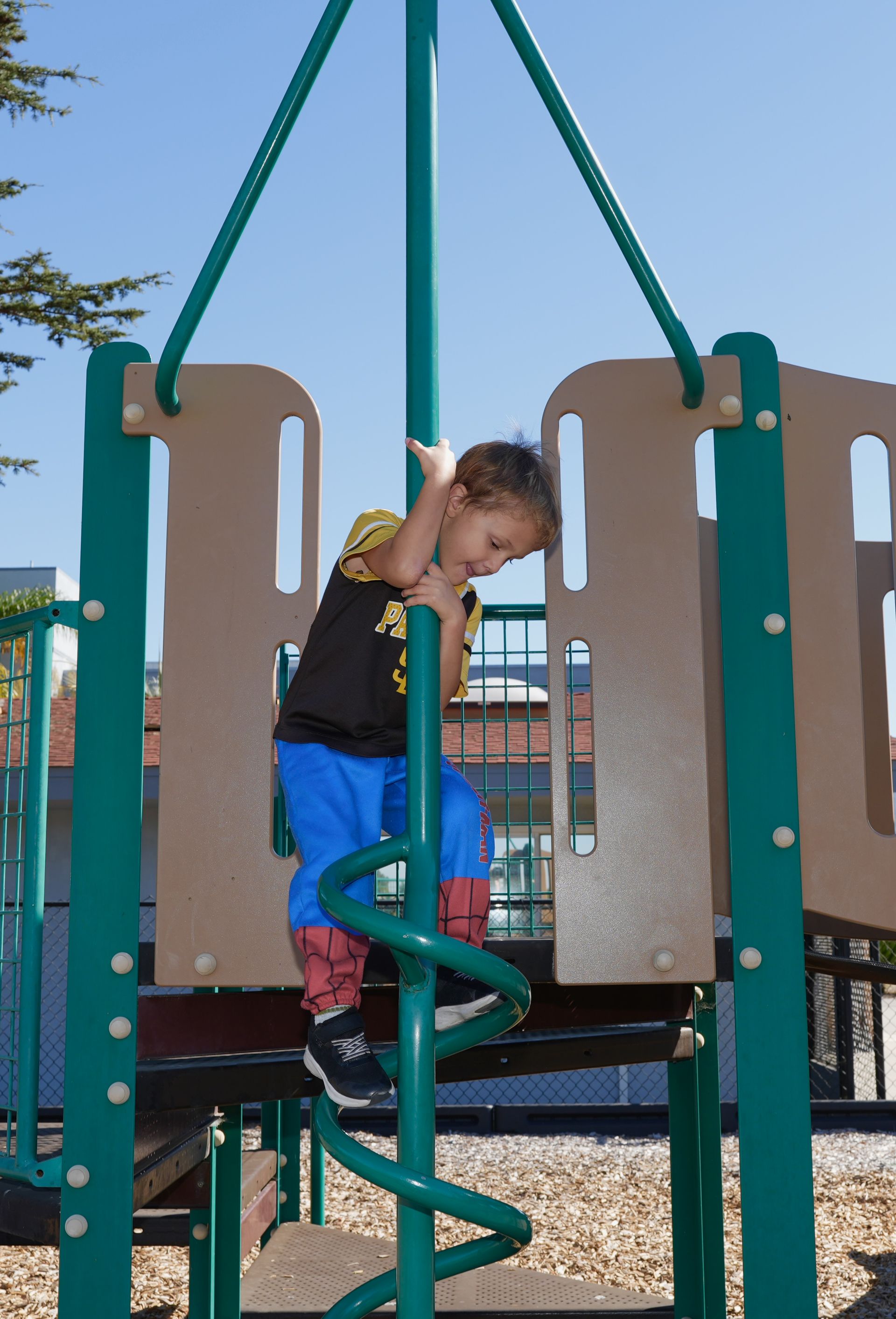 Child climbing a green spiral ladder on a playground play structure