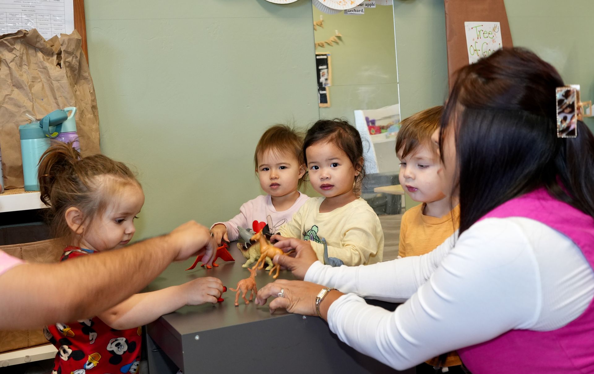 Children and adults around a table playing with a toy in a classroom setting