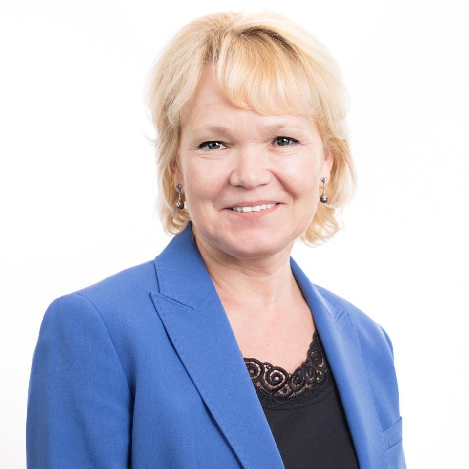 Portrait of a smiling person in a blue blazer and black top against a white background