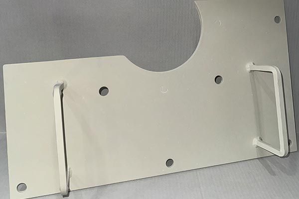 A white metal plate with a handle on it is sitting on a table. A white metal plate with a handle on it is sitting on a table.