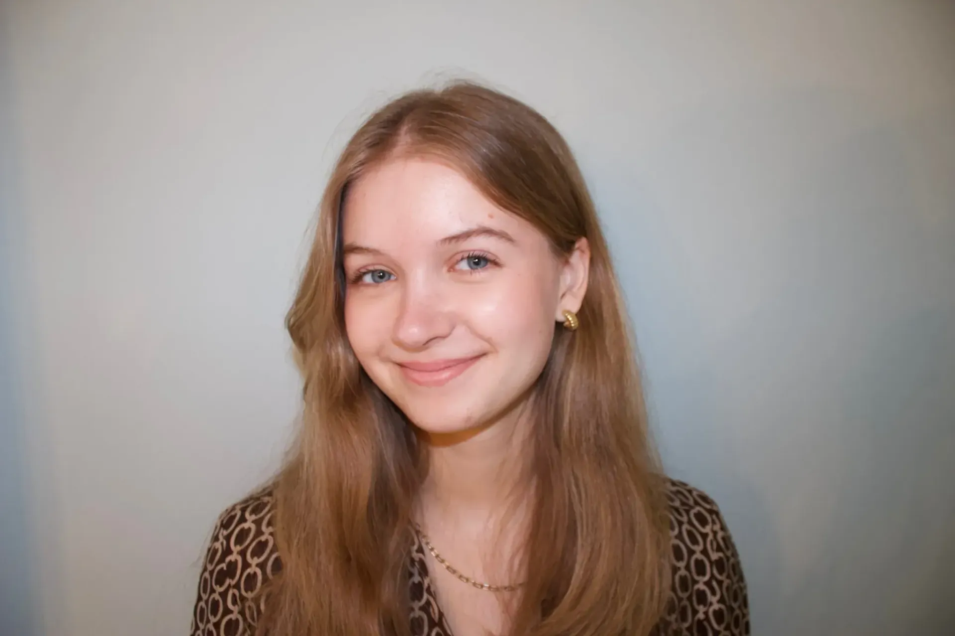 A young woman with long brown hair is smiling for the camera.