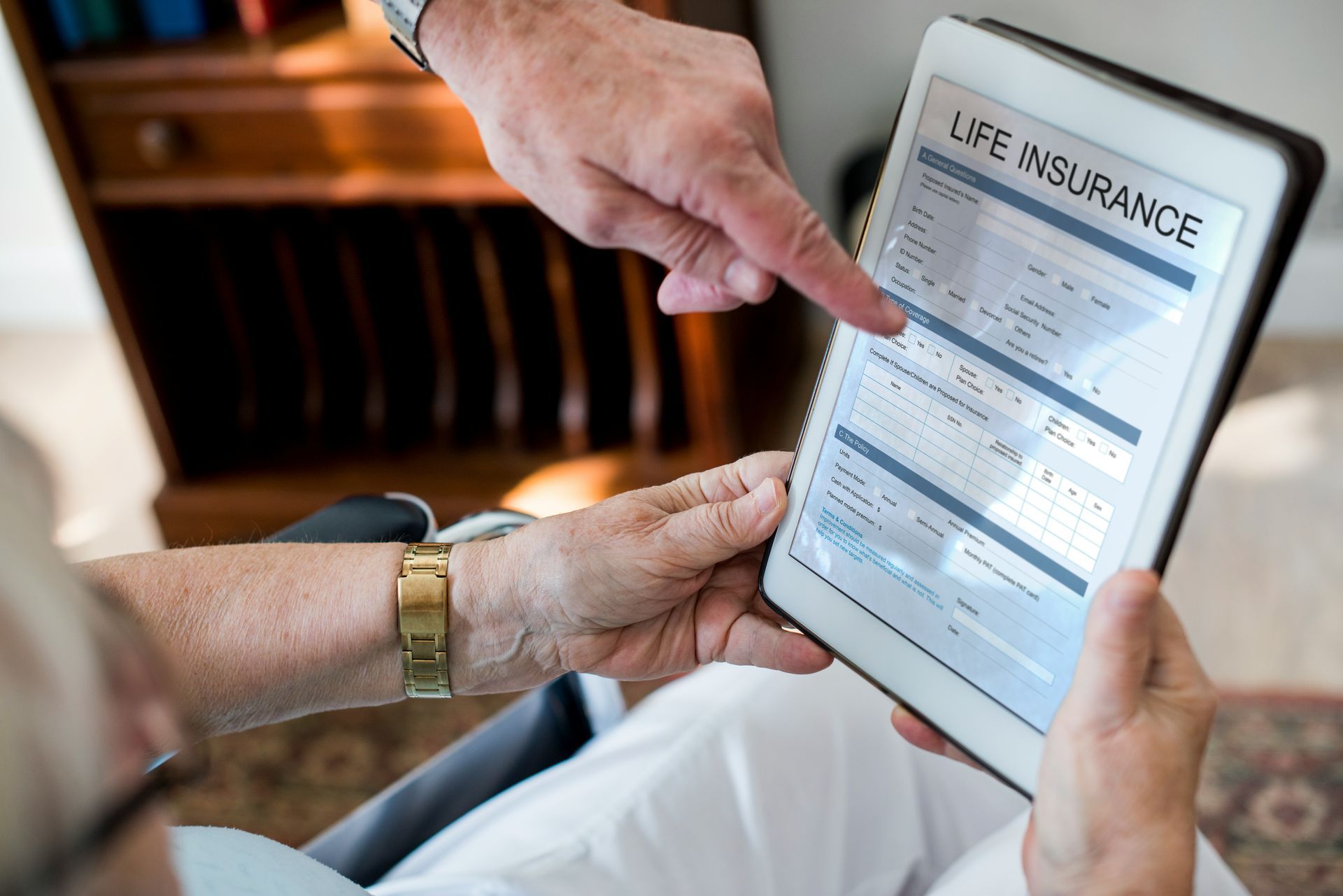 A man is pointing at a tablet with a life insurance form on it.