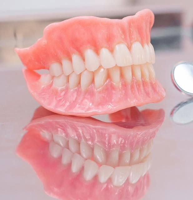 Denture is Sitting on Top of a Mirror on a Table — Cosmetic Denture Services–Jacob Maxwell in Proserpine, QLD