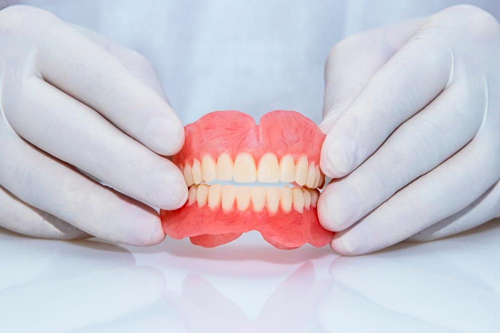 Person is Holding a Denture in Their Hands — Cosmetic Denture Services–Jacob Maxwell in Proserpine, QLD