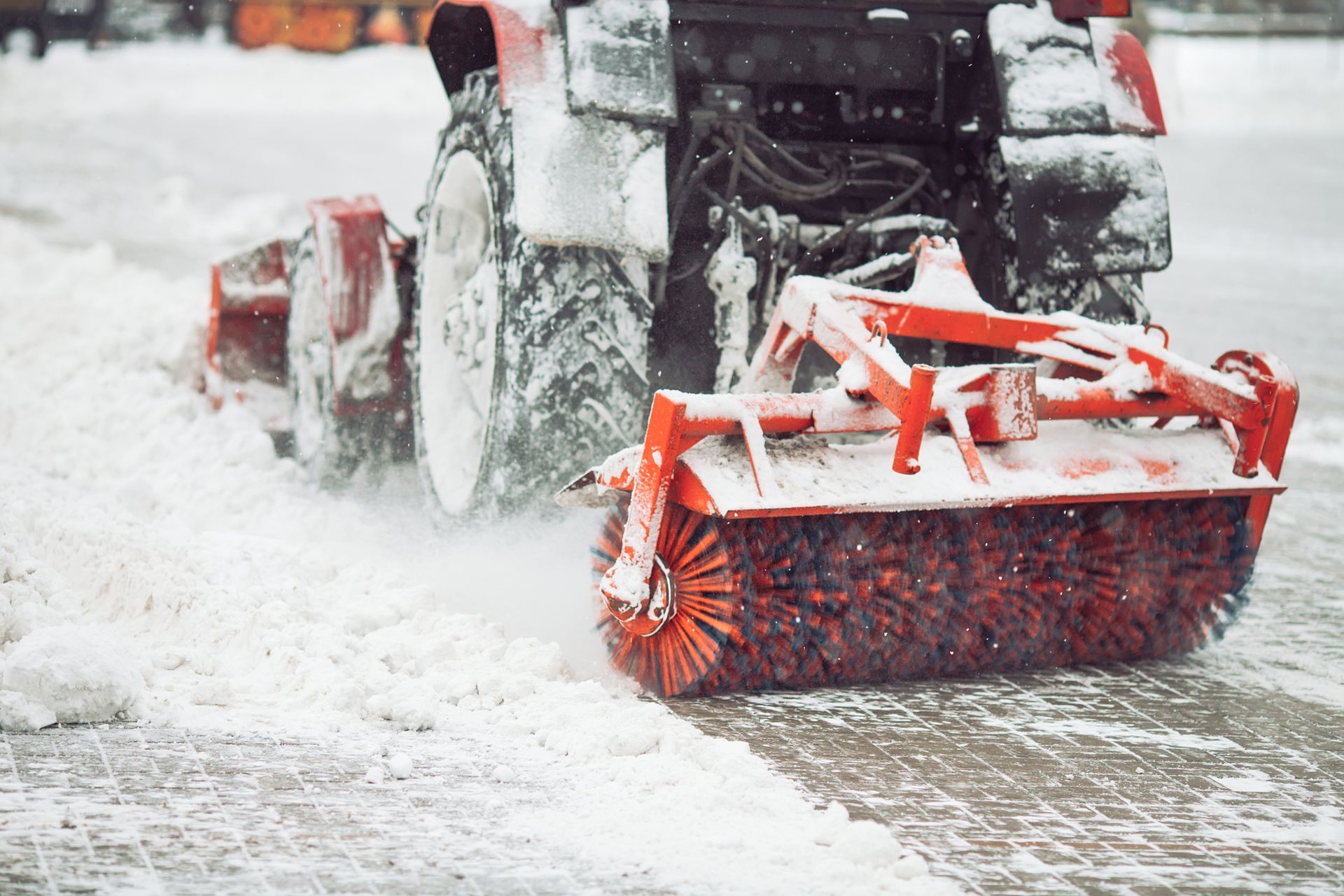Snowplow clearing a snowy road, with a red plow spraying snow forward