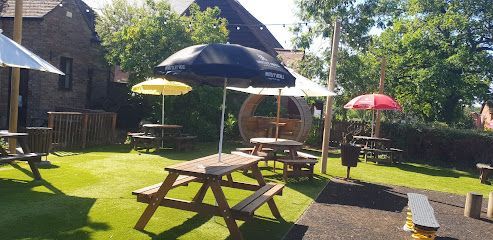 Sunny backyard with picnic tables, colorful umbrellas, and a grassy patio area