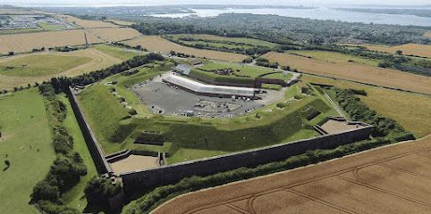 Aerial view of a historic stone fortress with grassy walls and surrounding farmland countryside.