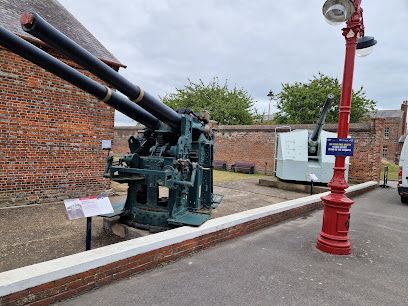 Historic black cannon on display beside a red lamppost in a brick courtyard.