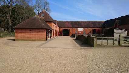 Red brick courtyard buildings with a gravel path and fenced area under a clear blue sky