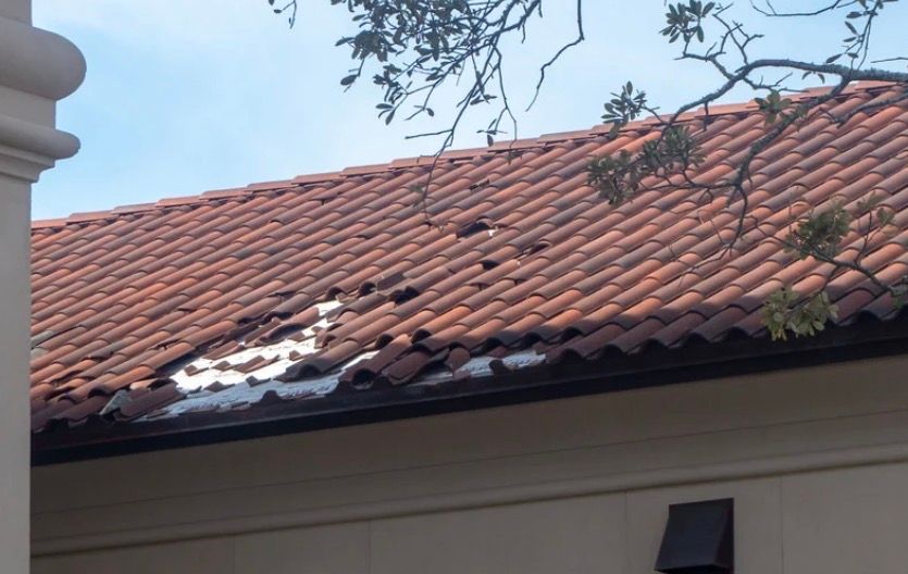 Terracotta tile roof with white snow patches on a building under a blue sky