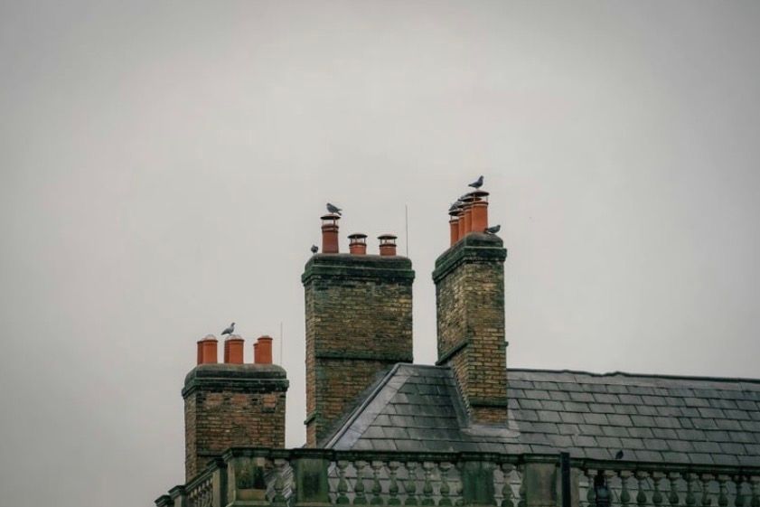 Old brick chimneys and slate rooftops against a gray sky