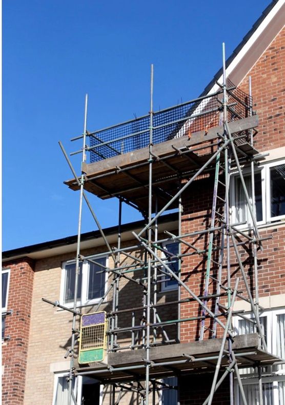 Scaffolding on a brick building under construction against a clear blue sky