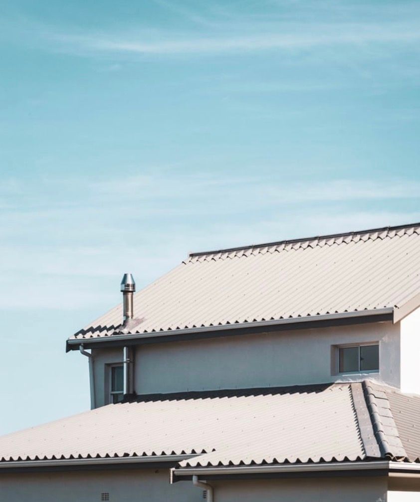 Two-story house with white roof against a clear blue sky