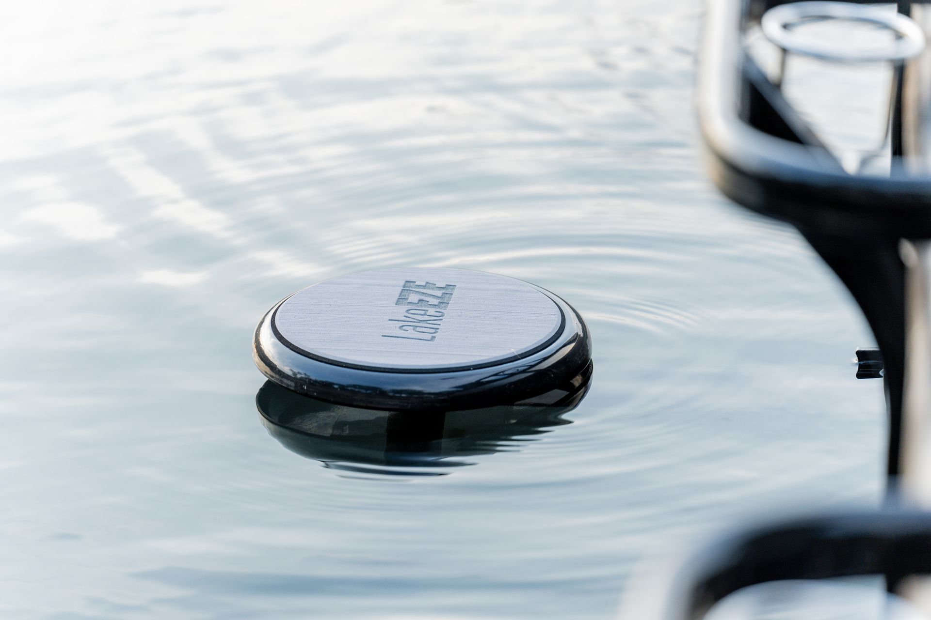 Round puck floating on calm water beside a boat rail