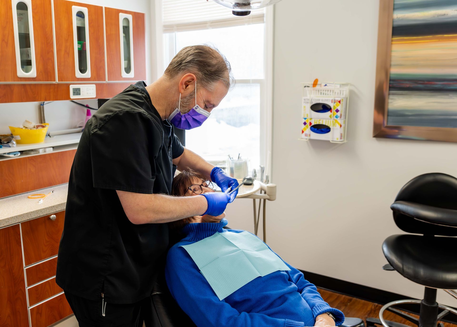Dentist in purple mask and gloves treating a patient in a dental chair