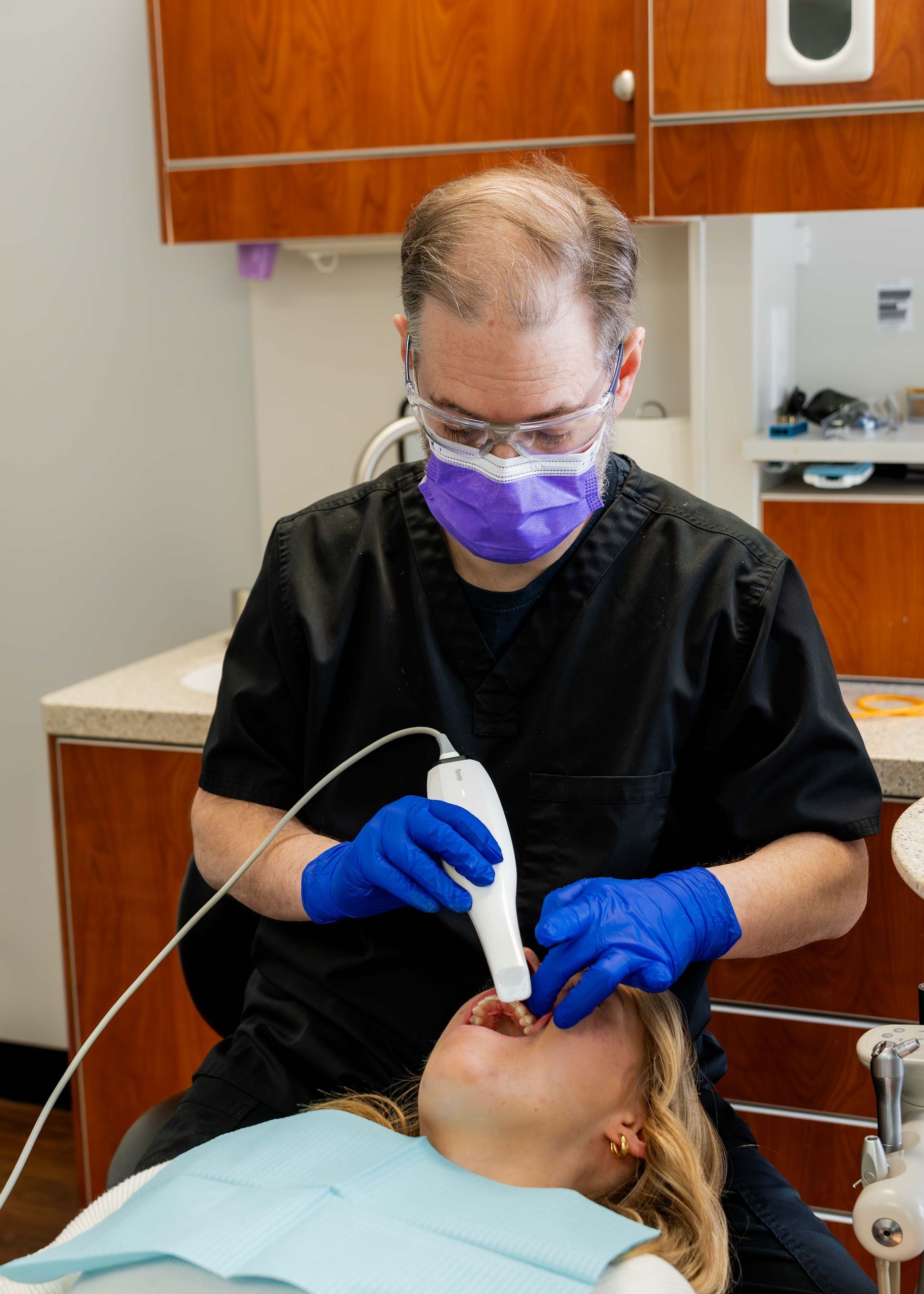Dentist in mask and gloves performing a dental procedure on a patient in a clinic chair.