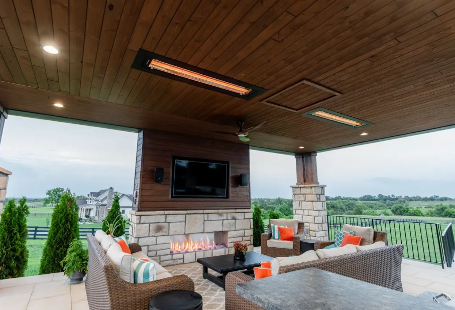 Covered outdoor patio with wicker seating, fireplace, TV, and view of a green landscape