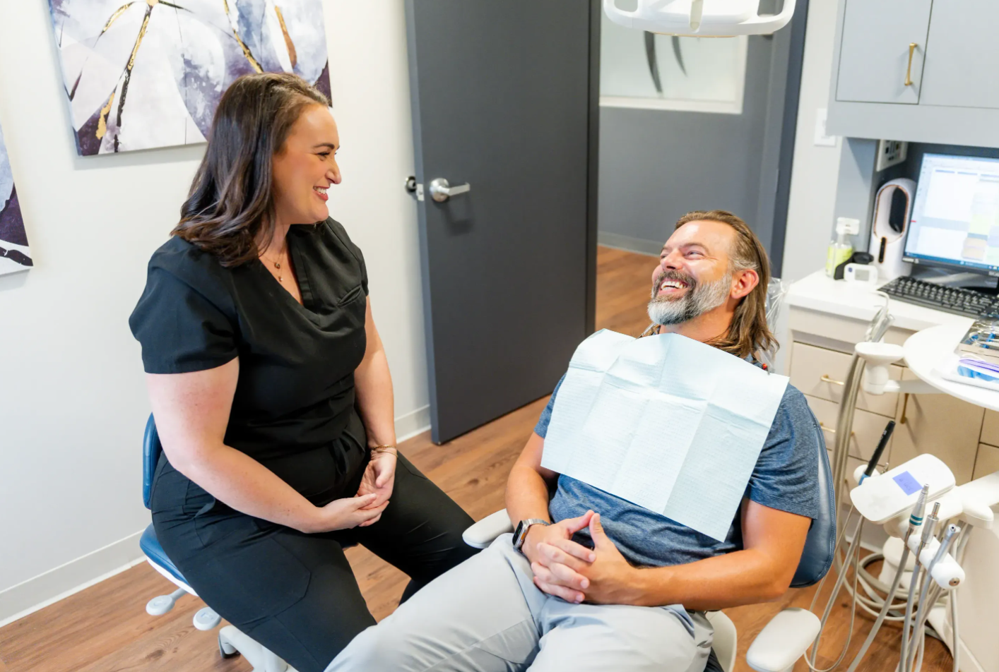 Dentist and patient smiling during a dental exam in a bright clinic room