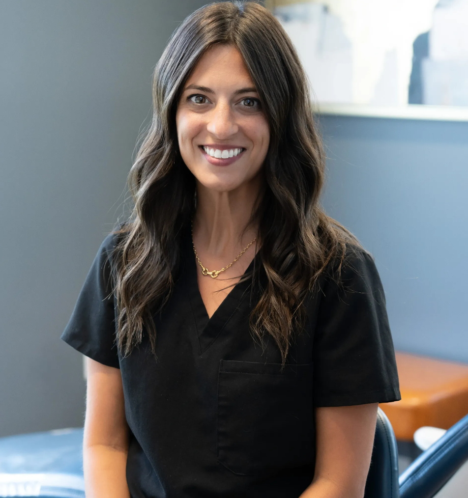 Smiling woman in black scrubs standing in a bright office or clinic room