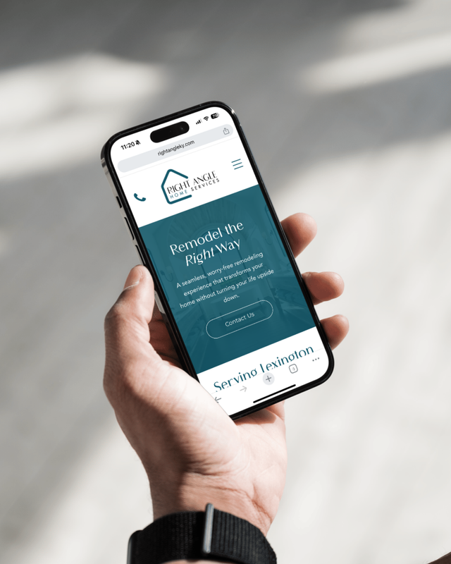 Hand holding a smartphone showing a teal website screen on a blurred floor background