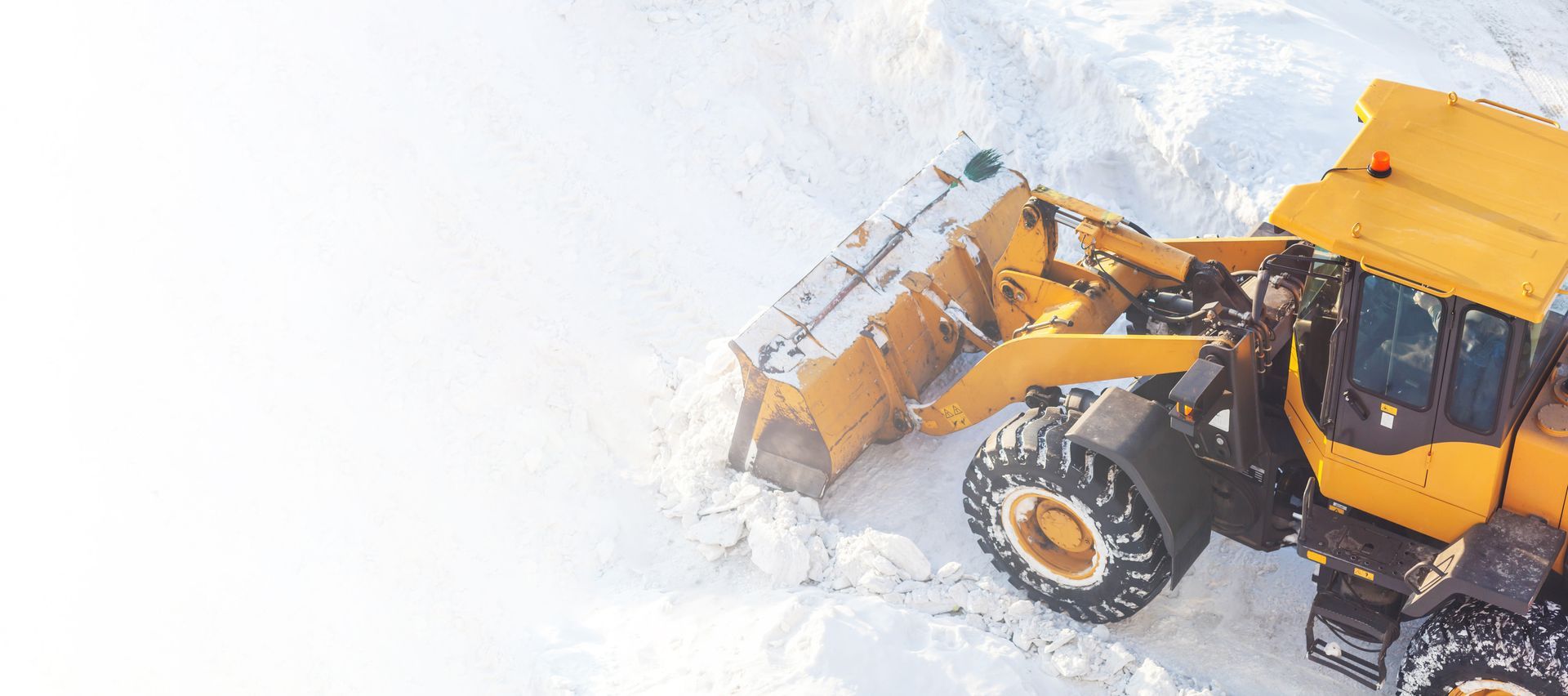 Yellow snowplow clearing deep snow on a road in winter