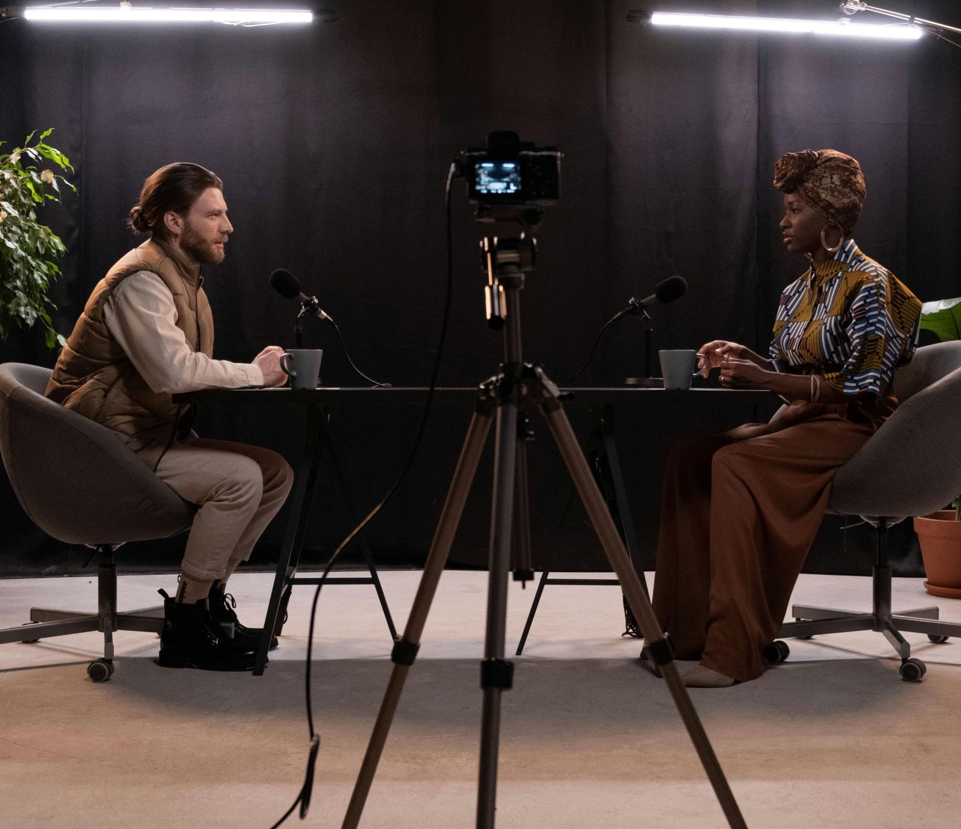 A man and a woman are sitting at a table in front of a camera.