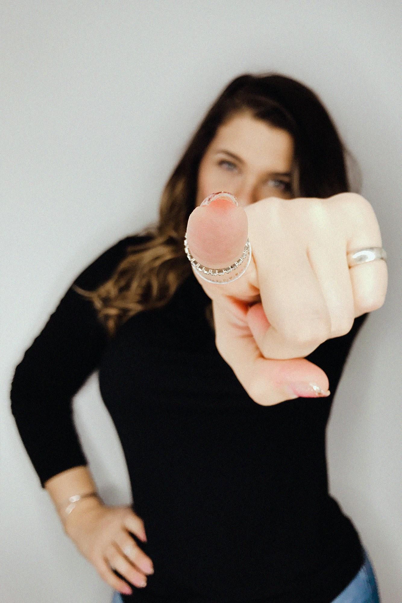 A woman with a ring on her finger is pointing at the camera