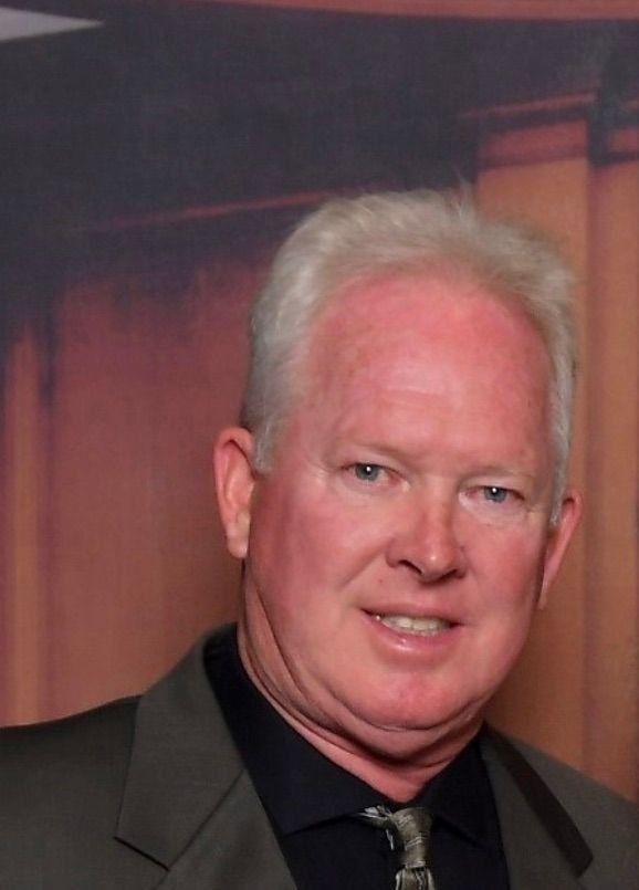 A man in a suit and tie is smiling for the camera