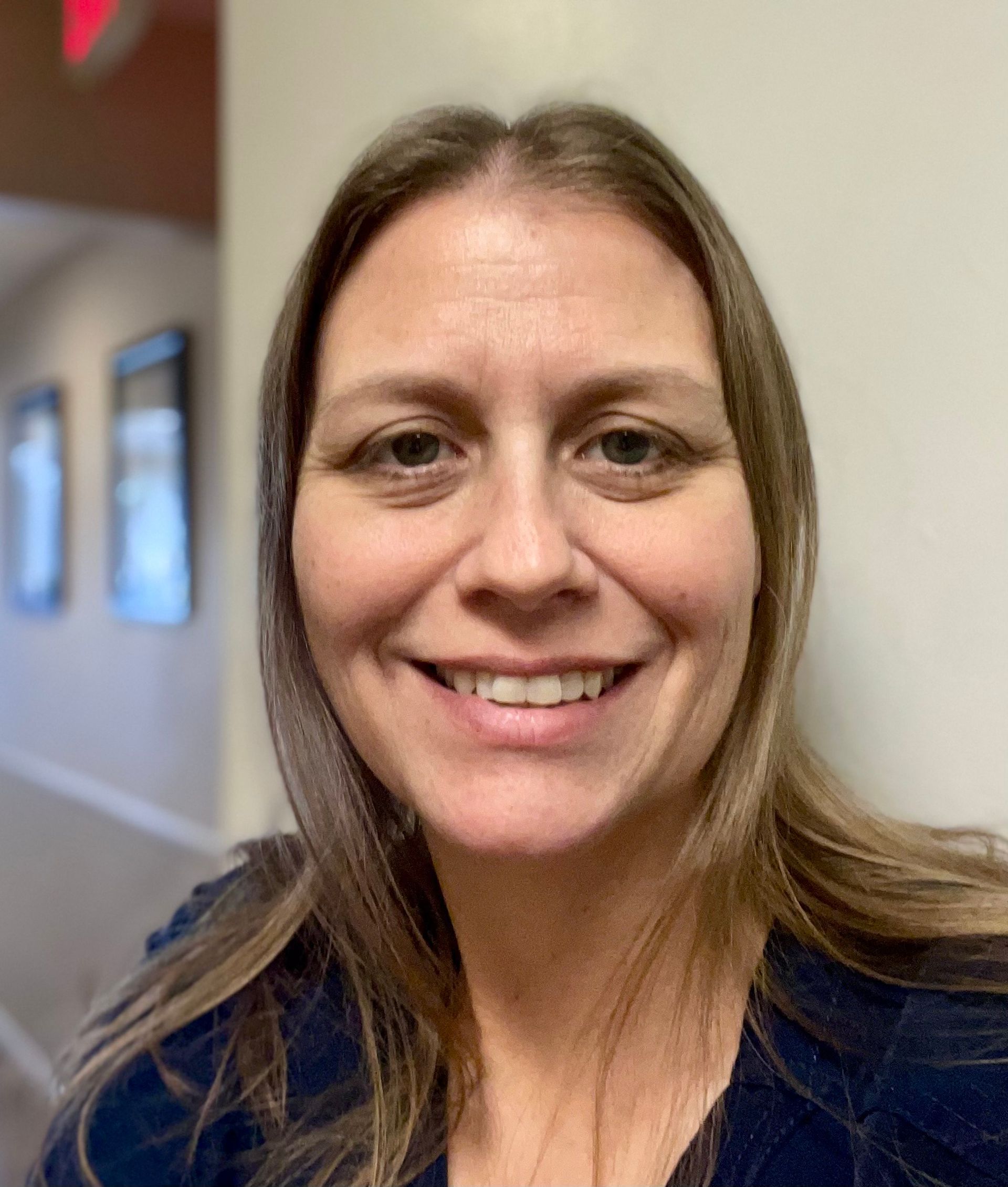 A woman is smiling for the camera in a hallway.