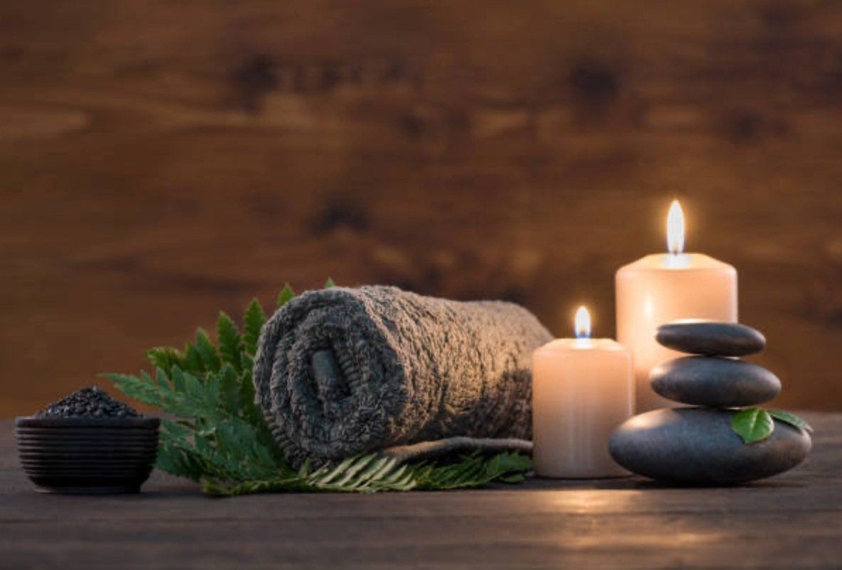 A wooden table topped with towels , candles , and rocks.