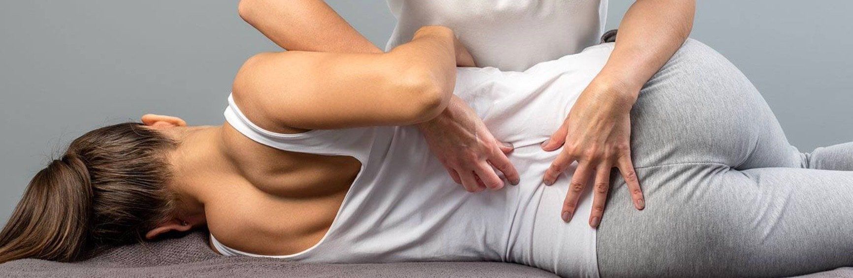 A woman is laying on her back getting a massage from a massage therapist.