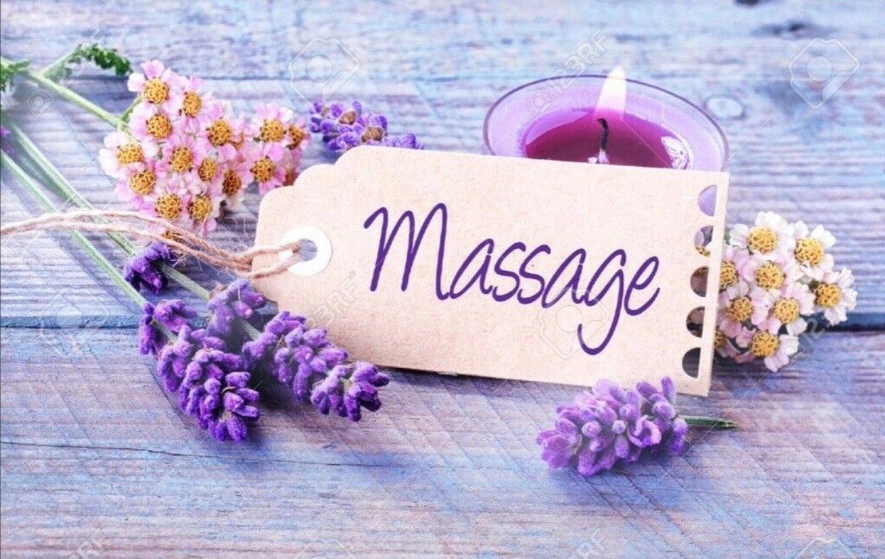 A massage tag with purple flowers and a candle on a wooden table.