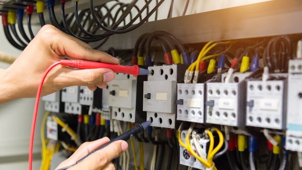 A Person Is Working On An Electrical Panel With A Multimeter — Cool & Secure In Noosa, QLD