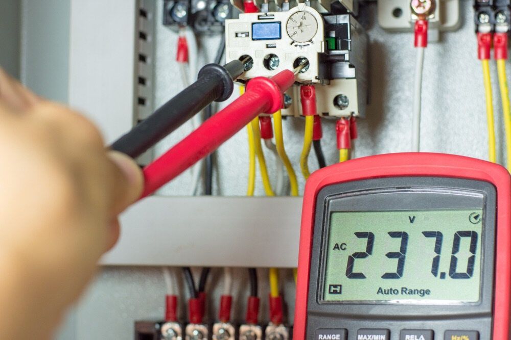 A Person Is Using A Multimeter To Measure Voltage In An Electrical Box — Cool & Secure In Maroochydore, QLD
