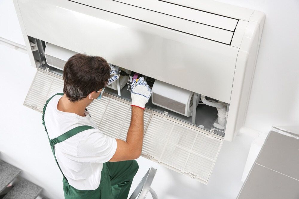 A Man Is Working On A Wall Mounted Air Conditioner — Cool & Secure In Maroochydore, QLD