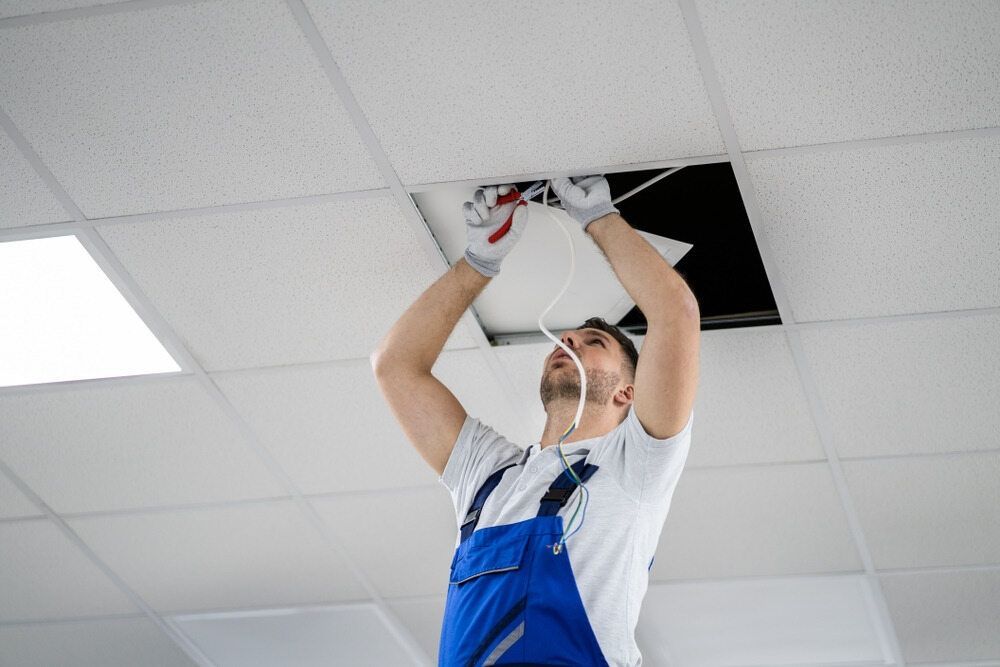 A Man Is Fixing A Light Fixture On The Ceiling — Cool & Secure In Warana, QLD