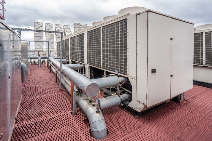 A Man In A Blue Shirt Is Working On An Air Conditioner — Cool & Secure In Maroochydore, QLD